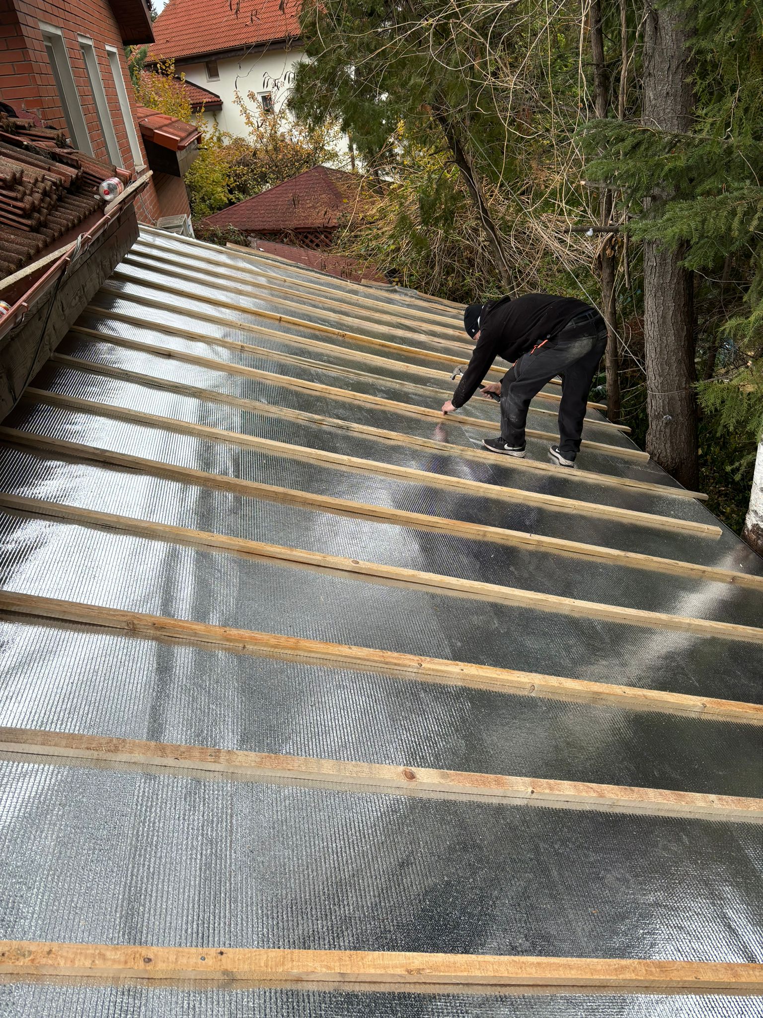 Montaj real al foliei anticondens Isoflect Roof Eco pe acoperișul unei case — folia reflectivă fixată cu șipci de lemn, înainte de învelitoare